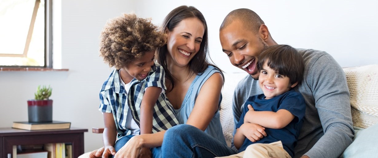 Famille souriant l'une à l'autre en s'asseyant sur le sofa.